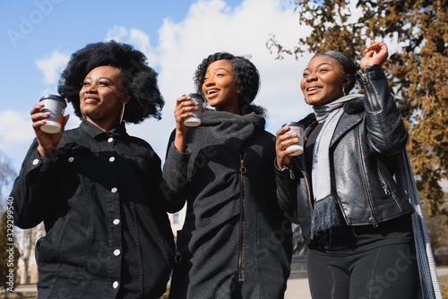 stylish african american girls drinking coffee on the street