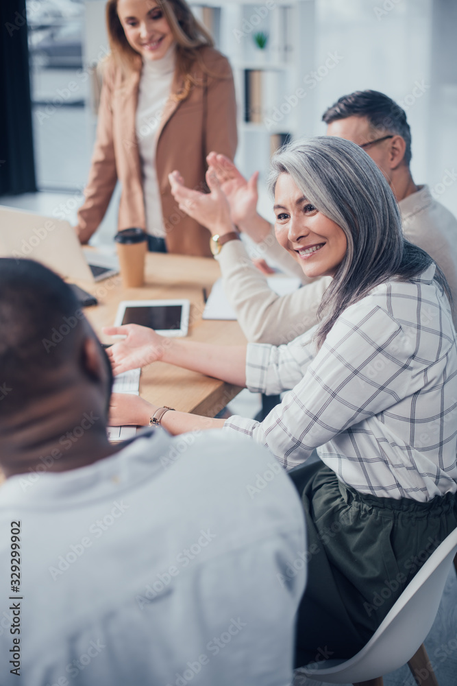 selective focus of smiling asian woman looking at her african american colleague during meeting selective focus of smiling asian woman looking at her african american colleague during meeting