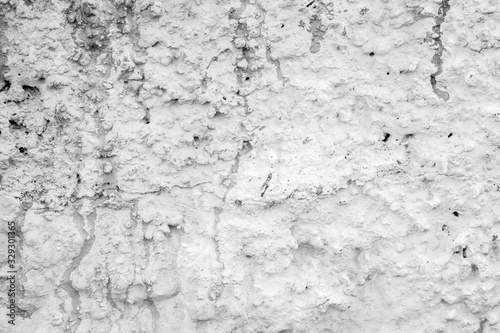 Close-up of a rough and plastered stucco wall painted in white. Drips and stains of paint. High resolution full frame textured background in black and white.