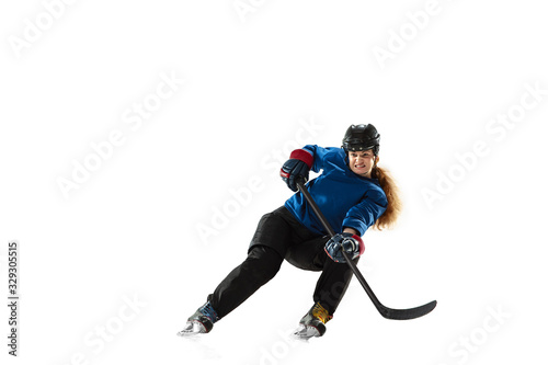 Obraz na płótnie Young female hockey player with the stick on ice court and white background. Sportswoman wearing equipment and helmet training. Concept of sport, healthy lifestyle, motion, action, human emotions. w salonie