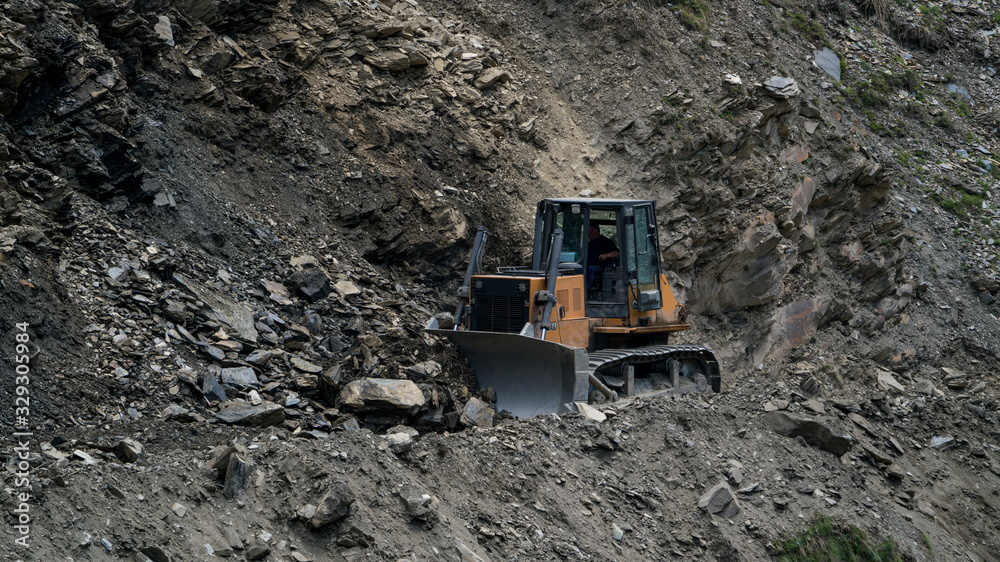 Tractor clearing the road from rockfall summer Tractor clearing the road from rockfall summer