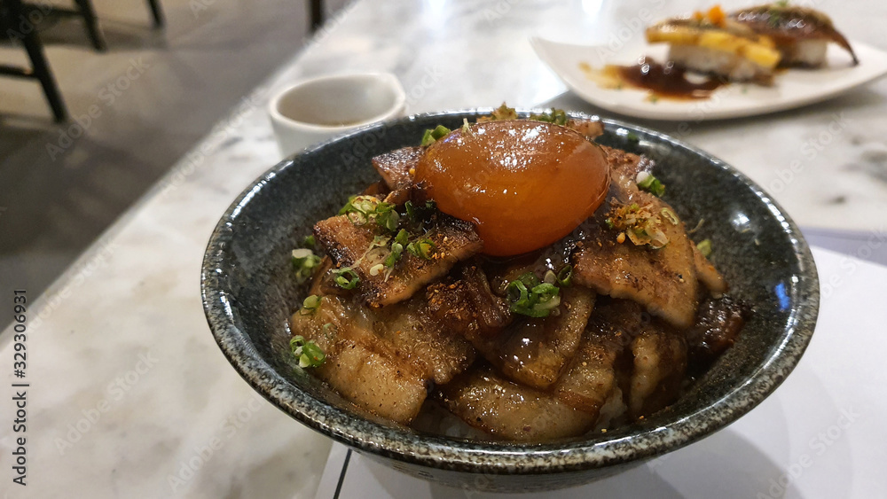 Roasted pork belly sliced with Japanese sauce with Soy sauce raw egg yolk on white rice Roasted pork belly sliced with Japanese sauce with Soy sauce raw egg yolk on white rice