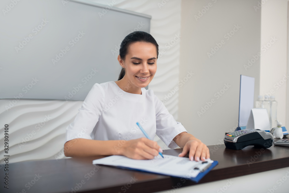 Dark-haired appealing manager of beauty clinic making notes Dark-haired appealing manager of beauty clinic making notes