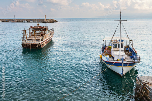 view of small fishing boats parked in a quiet bay of the Greek city of Hersonissos against a blue sky