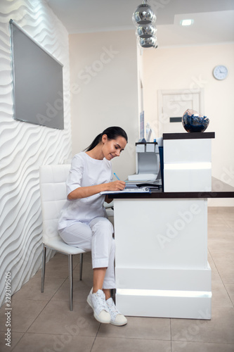 Receptionist wearing white uniform and sneakers making notes