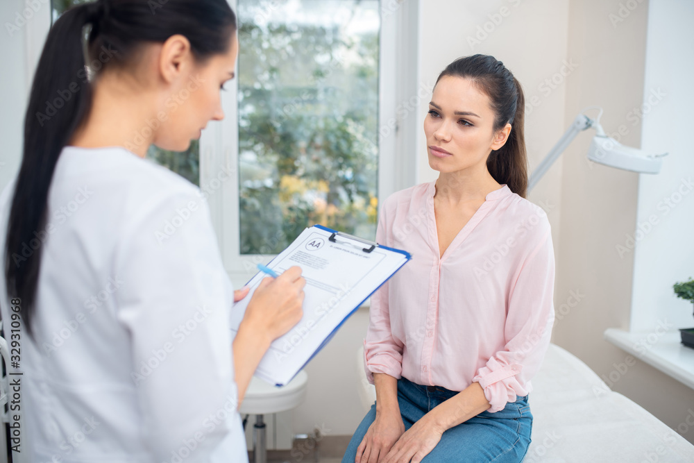 Businesswoman talking to plastic surgeon while having appointment Businesswoman talking to plastic surgeon while having appointment