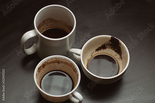  dirty empty cups of coffee after drinking on a wooden black table
