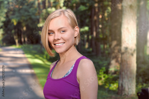 Portrait of young smilling sporty woman running in the fores outdoor early in the morning