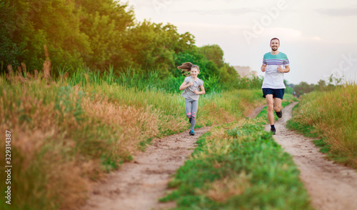 Father and daughter jogging. Cheerful father and daughter run in park together.