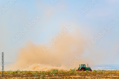 Ein Traktor pflügt ein trockenes Feld an einem heißen Tag.