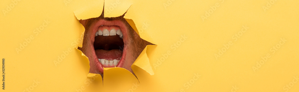 cropped view of open mouth in yellow paper hole - obrazy, fototapety, plakaty 