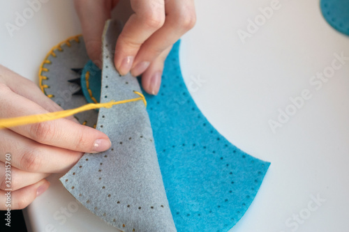 A girl sews an owl toy from felt. Cute stuffed toy is made manually. Easy sewing project for kids