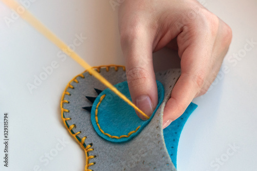 A girl sews an owl toy from felt. Cute stuffed toy is made manually. Easy sewing project for kids