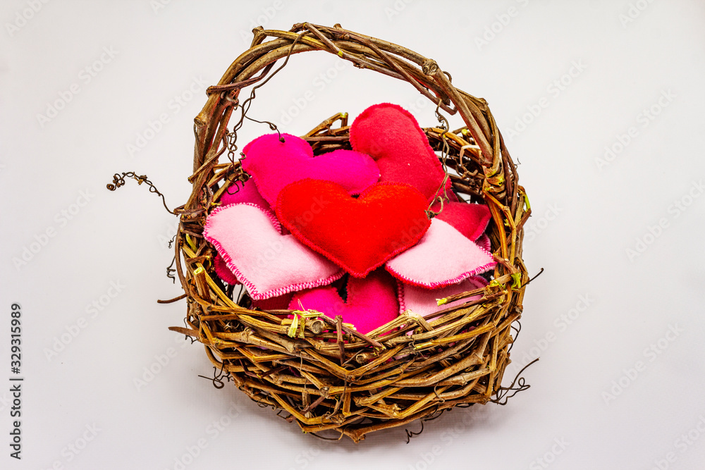 Colored felt hearts in wicker basket isolated on white background. Valentines Day or Wedding romantic concept Colored felt hearts in wicker basket isolated on white background. Valentines Day or Wedding romantic concept