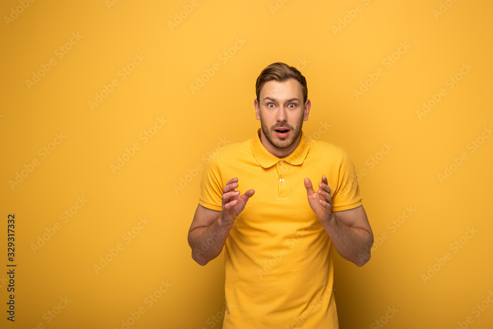 shocked handsome man in yellow outfit gesturing on yellow background shocked handsome man in yellow outfit gesturing on yellow background