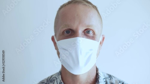 The young man defends himself against the 2020 virus coronavirus and other infections. He sits in a mask and shows bad and displeased emotions about the epidemic.