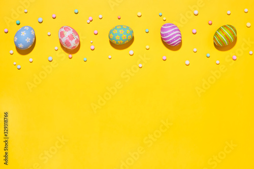 Creative Easter holiday layout eggs colored handmade paint ed with ribbon foam party on yellow background.Seasonal flat lay concept.