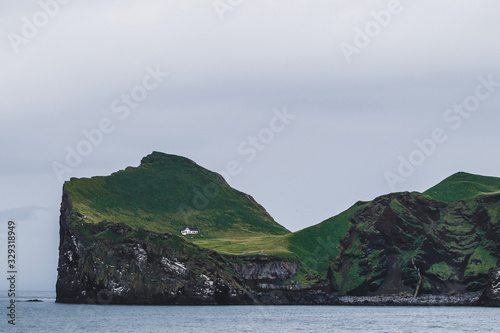 Lonely house on Ellidaey island in Vestmannaeyjar archipelago, Iceland. Rocky and green island. Nordic landscape. photo