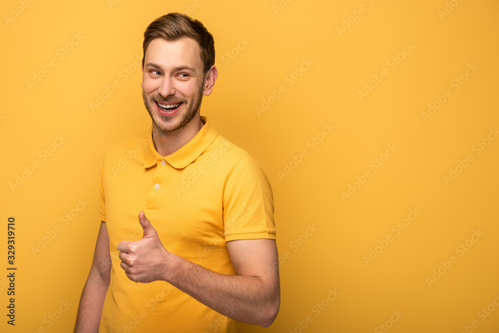 happy handsome man in yellow outfit showing thumb up on yellow background happy handsome man in yellow outfit showing thumb up on yellow background