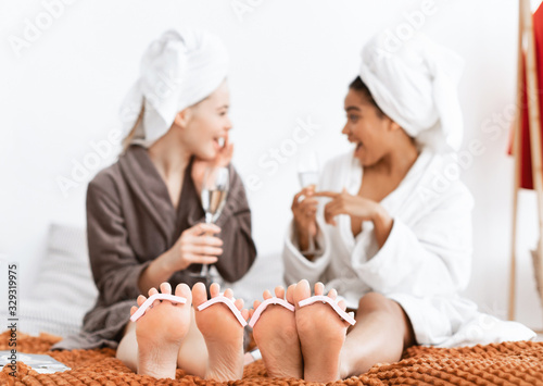 Girlfriends making pedicure and drinking champagne at home