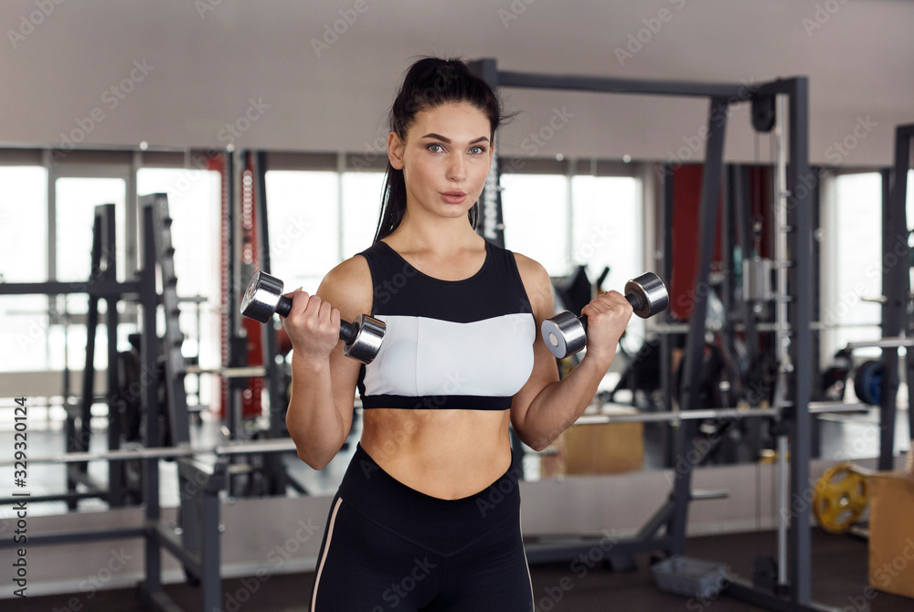 Strong woman working out with dumbbells in sports club Strong woman working out with dumbbells in sports club