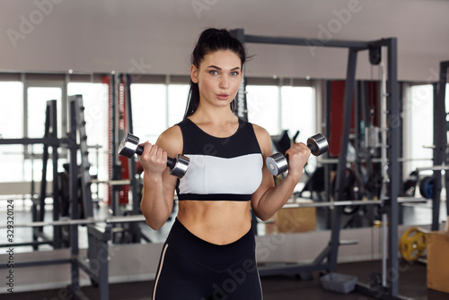 Strong woman working out with dumbbells in sports club