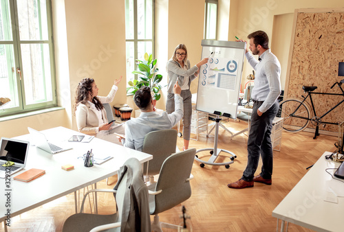 Group of young business people working together in office, two coworker conducting a business presentation using flip chart.