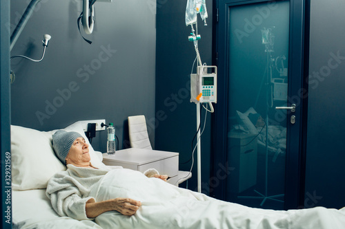 Elderly woman in a oncology clinic ward receiving chemotherapy treatment. IV drip for chemotherapy. Cancer. Oncology