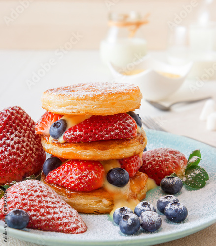 Mille Feuille, puff pastry discs with giant strawberries and blueberries with lemon curd. Gordon Ramsay recipe. Delicious French dessert with summer berries.