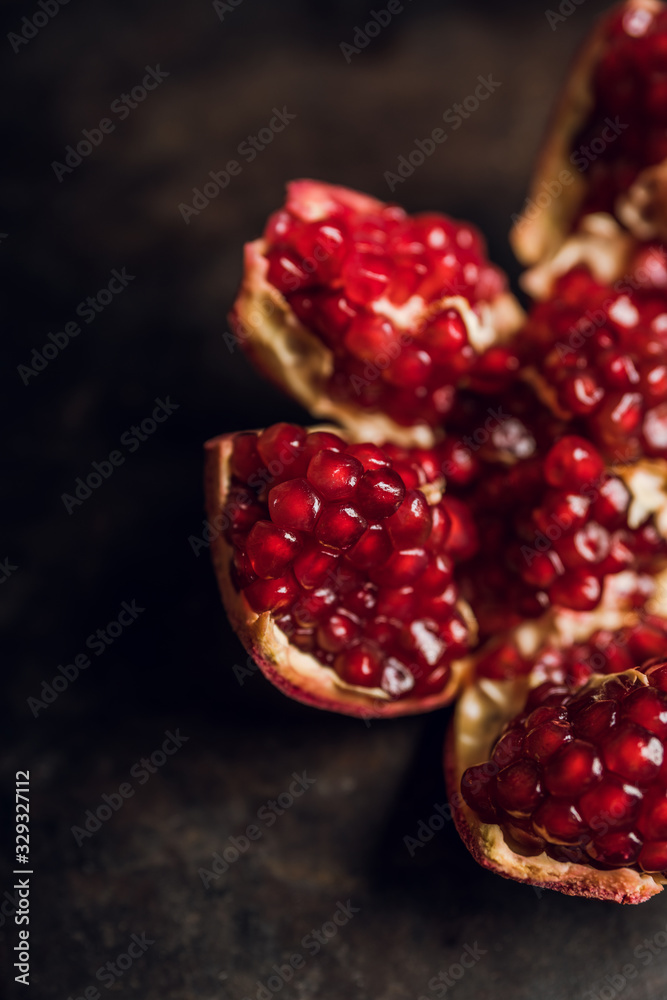 Broken red ripe pomegranate fruit on the dark rustic background. Selective focus. Shallow depth of field. Broken red ripe pomegranate fruit on the dark rustic background. Selective focus. Shallow depth of field.