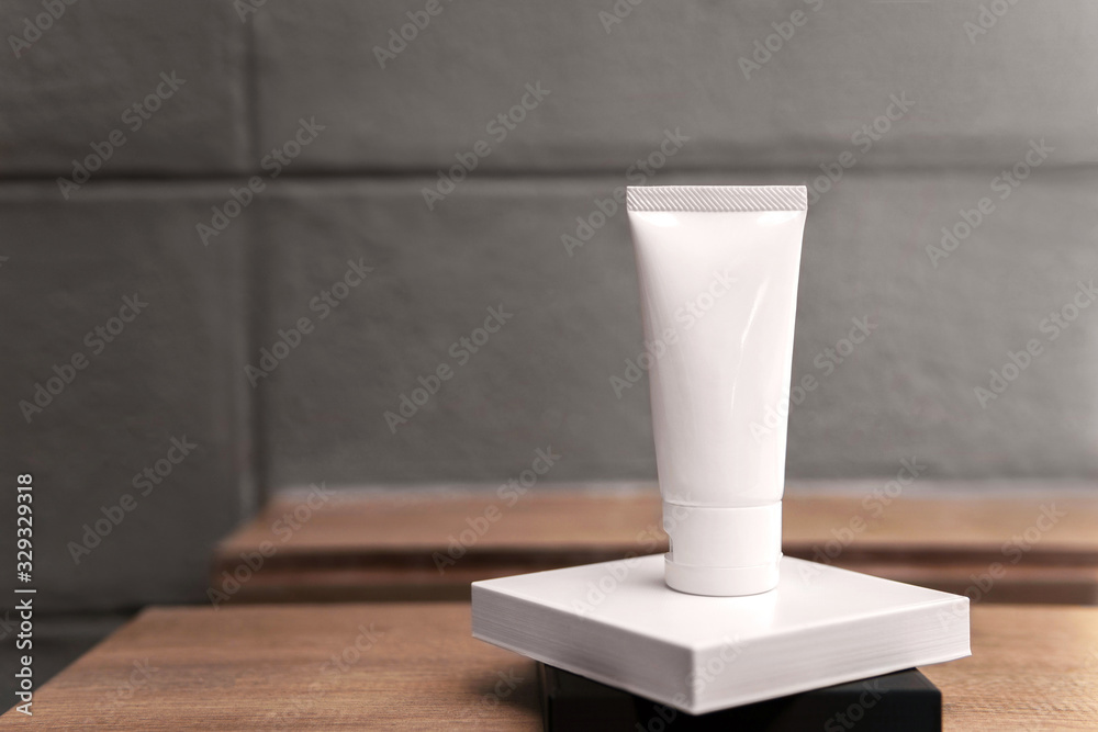 Empty treatment facial skincare white tube product with a blank label bottle sitting on white and black square pedestal with copy space and plain grey wall minimal and loft style as a background. Empty treatment facial skincare white tube product with a blank label bottle sitting on white and black square pedestal with copy space and plain grey wall minimal and loft style as a background.