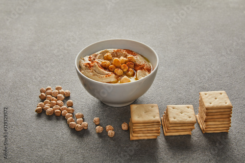 Fényképezés Bowl with delicious hummus, chickpea and crackers on grey