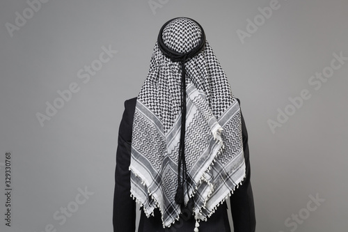 Back rear view of young arabian muslim businessman in keffiyeh kafiya ring igal agal classic black suit isolated on gray wall background studio portrait. Achievement career wealth business concept. photo
