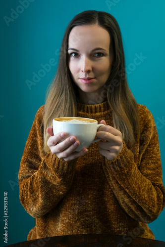 Portrait woman with latte on turquoise.