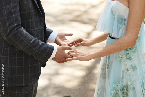 Close view of male and female hands. Young businessman holding hands of a young woman. Closeup cropped photo of two young lovers holding hands. Handsome groom holding hands of a young bride.
