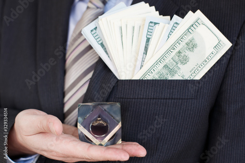 Businessman in suit, tie holds in hands drop of black oil of Brent brand in crystal cube.Pack of hundred dollars bills.Crisis in financial market,falling,rising prices,quotes,changes in exchange rate