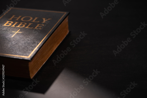 holy bible on black dark background with sunlight