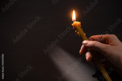 cropped view of woman holding burning church candle in dark