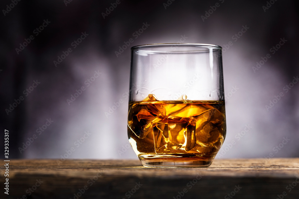 Faceted glass of whiskey with ice