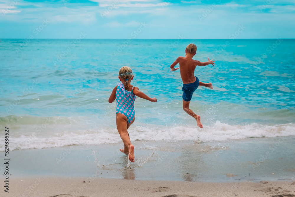 happy boy and girl run swim on beach