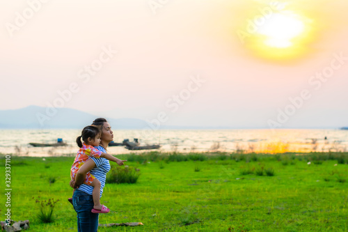 Mother and child stood by the river with the setting sun setting.