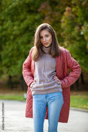 Close up portrait of a young beautiful brunette woman in coral coat © Andrey_Arkusha
