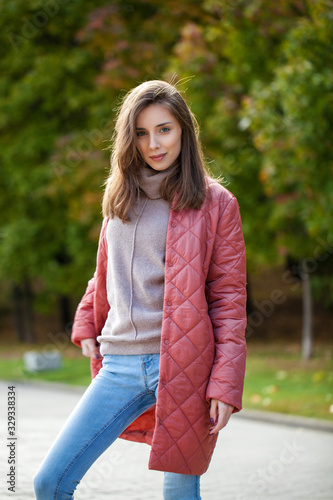 Close up portrait of a young beautiful brunette woman in coral coat © Andrey_Arkusha