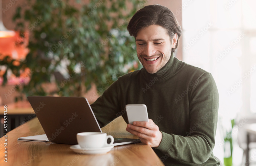 Wealthy young businessman using phone while working at cafe Wealthy young businessman using phone while working at cafe