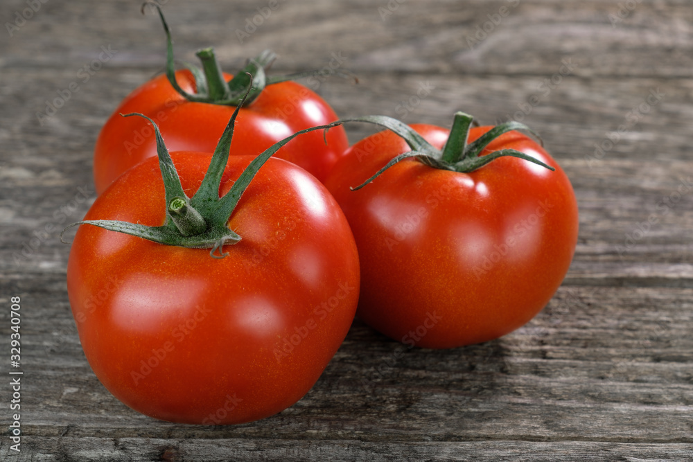 Drei frische rote Tomaten auf rustikalem Holzuntergrund Drei frische rote Tomaten auf rustikalem Holzuntergrund