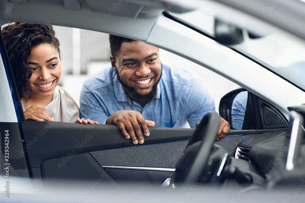 Couple Looking At Car Interior Buying Family Automobile In Dealership