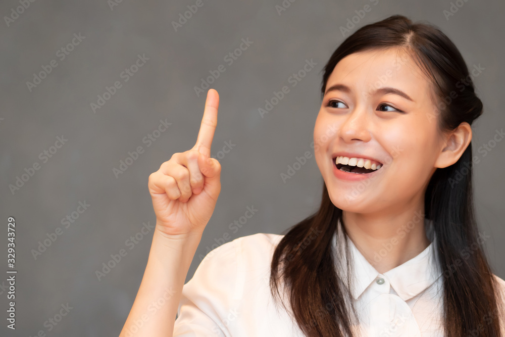asian woman pointing one finger; portrait of positive happy smiling asian woman pointing up one finger for first winner concept ; Chinese, east asian adult woman model, casual theme asian woman pointing one finger; portrait of positive happy smiling asian woman pointing up one finger for first winner concept ; Chinese, east asian adult woman model, casual theme