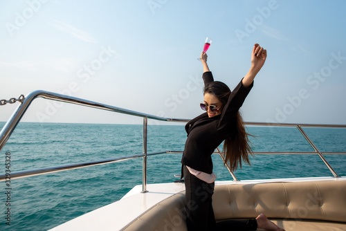 Luxury asian woman in black suit drinking champagne on the yacht.