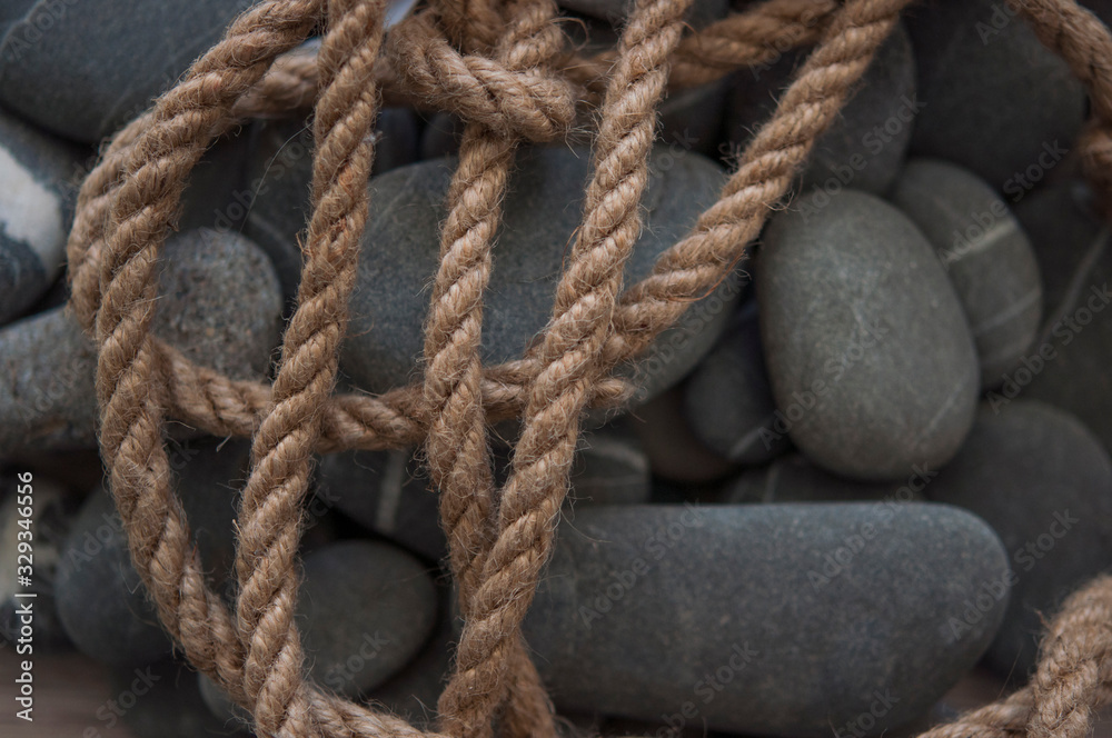 Fototapeta premium many gray pebbles with hemp rope background, space for text.