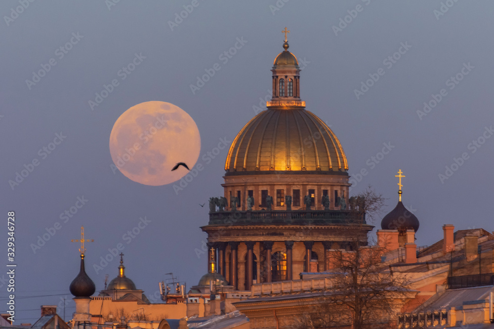 Evening view of the moon rising from the horizon and St. Isaac's Cathedral in the city of St. Petersburg.
